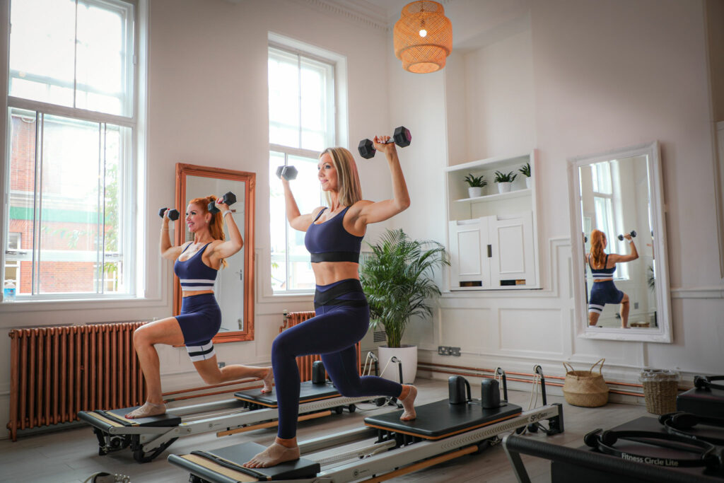 Korin & Tiffany using weights on a reformer in the studio